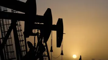 ناقلة نفط وسط البحر مع برج حفر نفطي في الخلفية